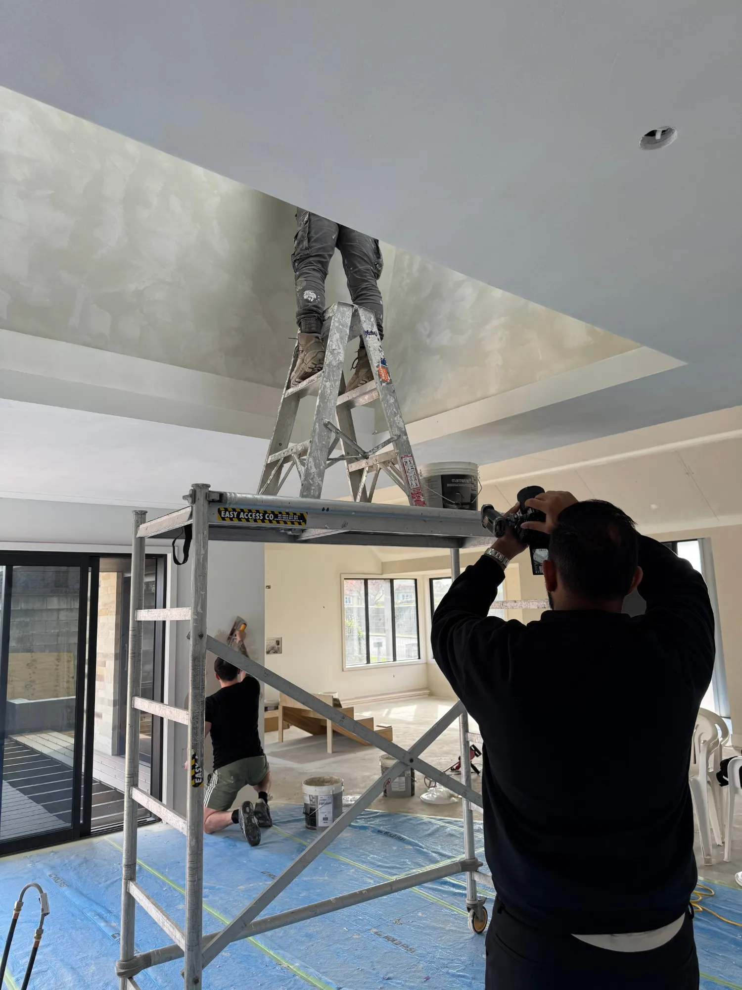 Bhawin Mistry filming plasterers at work on a ceiling