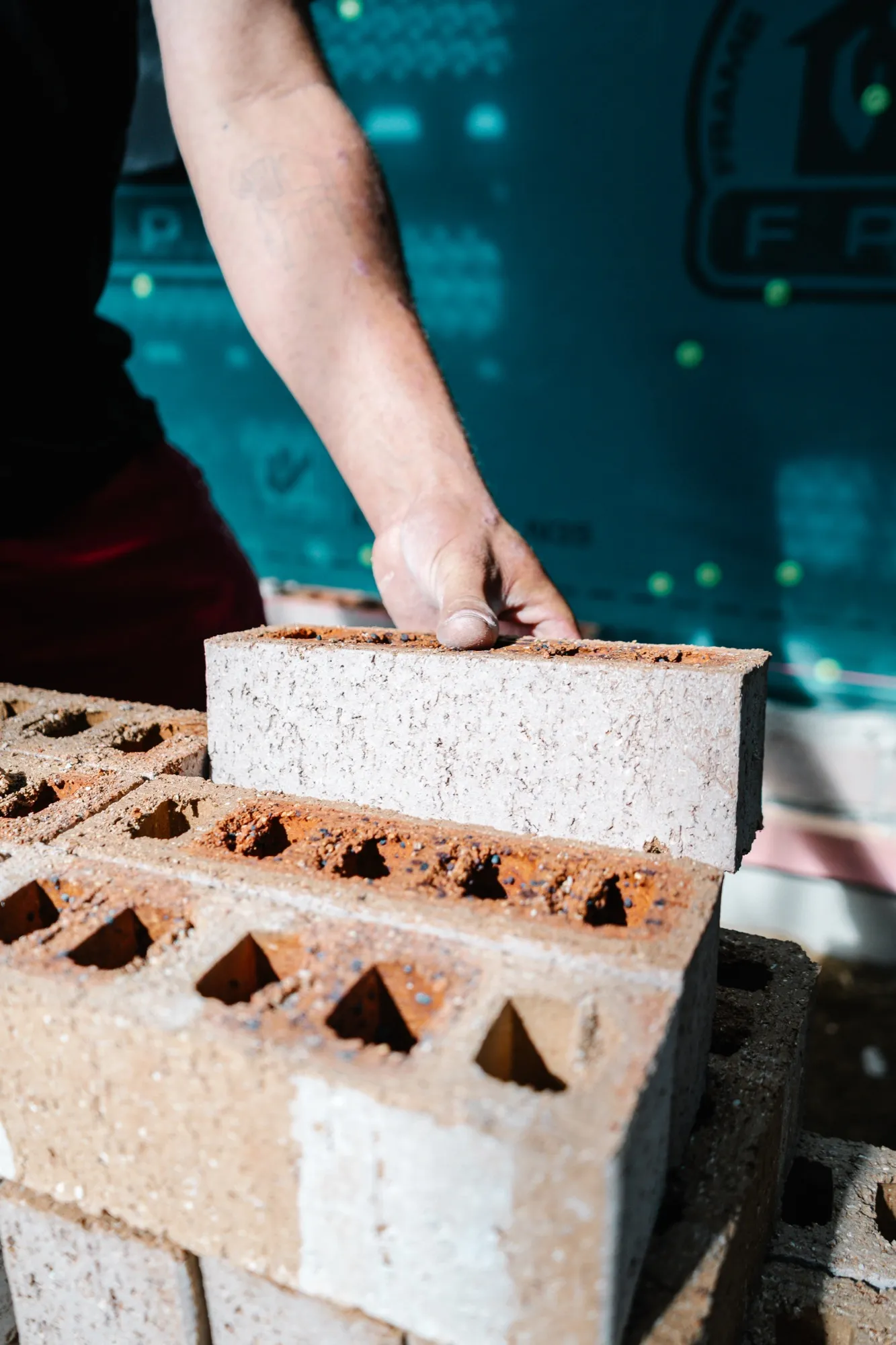 Close-up of a hand setting a brick onto the course