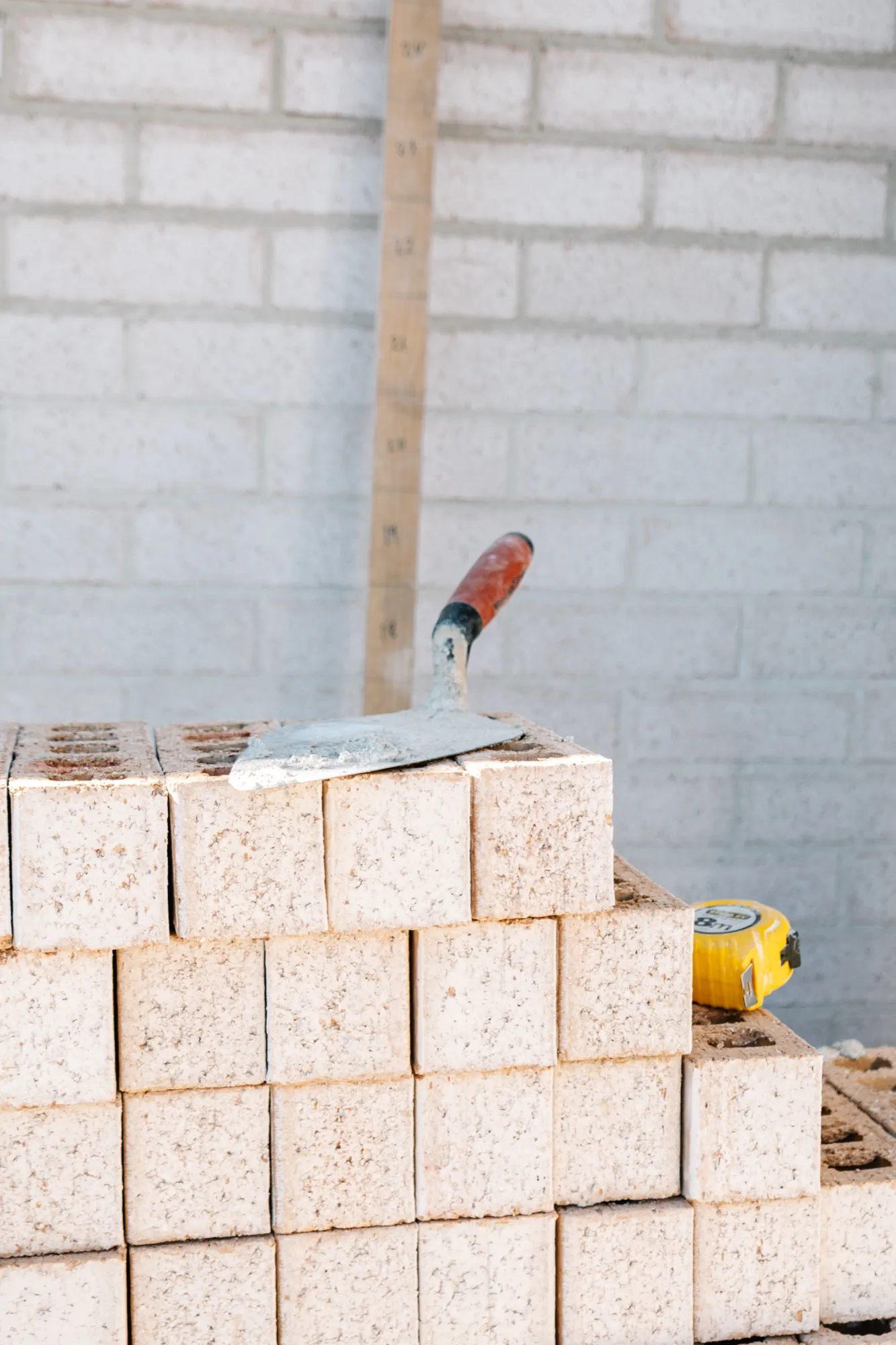 A trowel resting on a stack of bricks against the finished wall