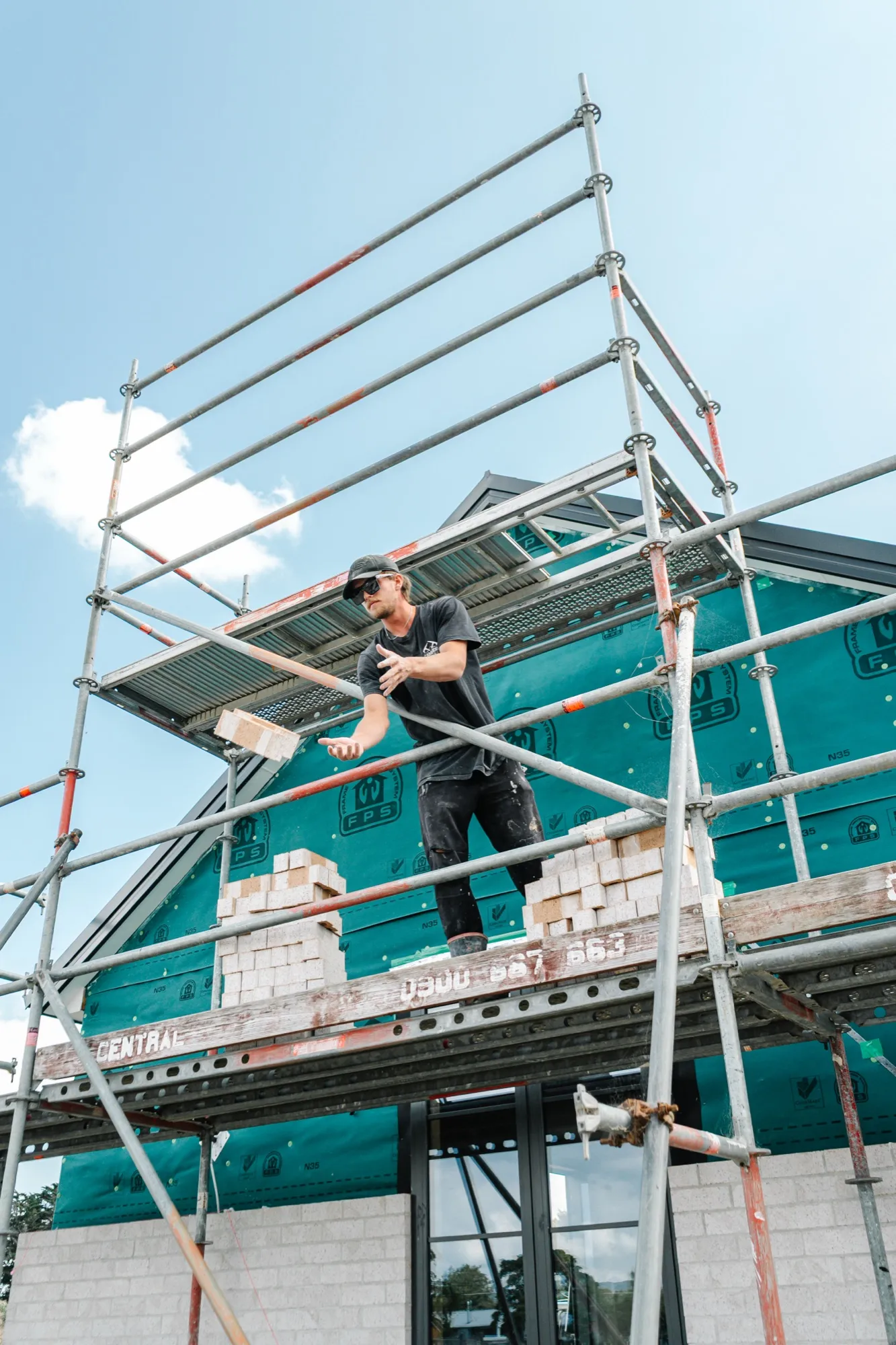 A bricklayer working up on the scaffold against the gable