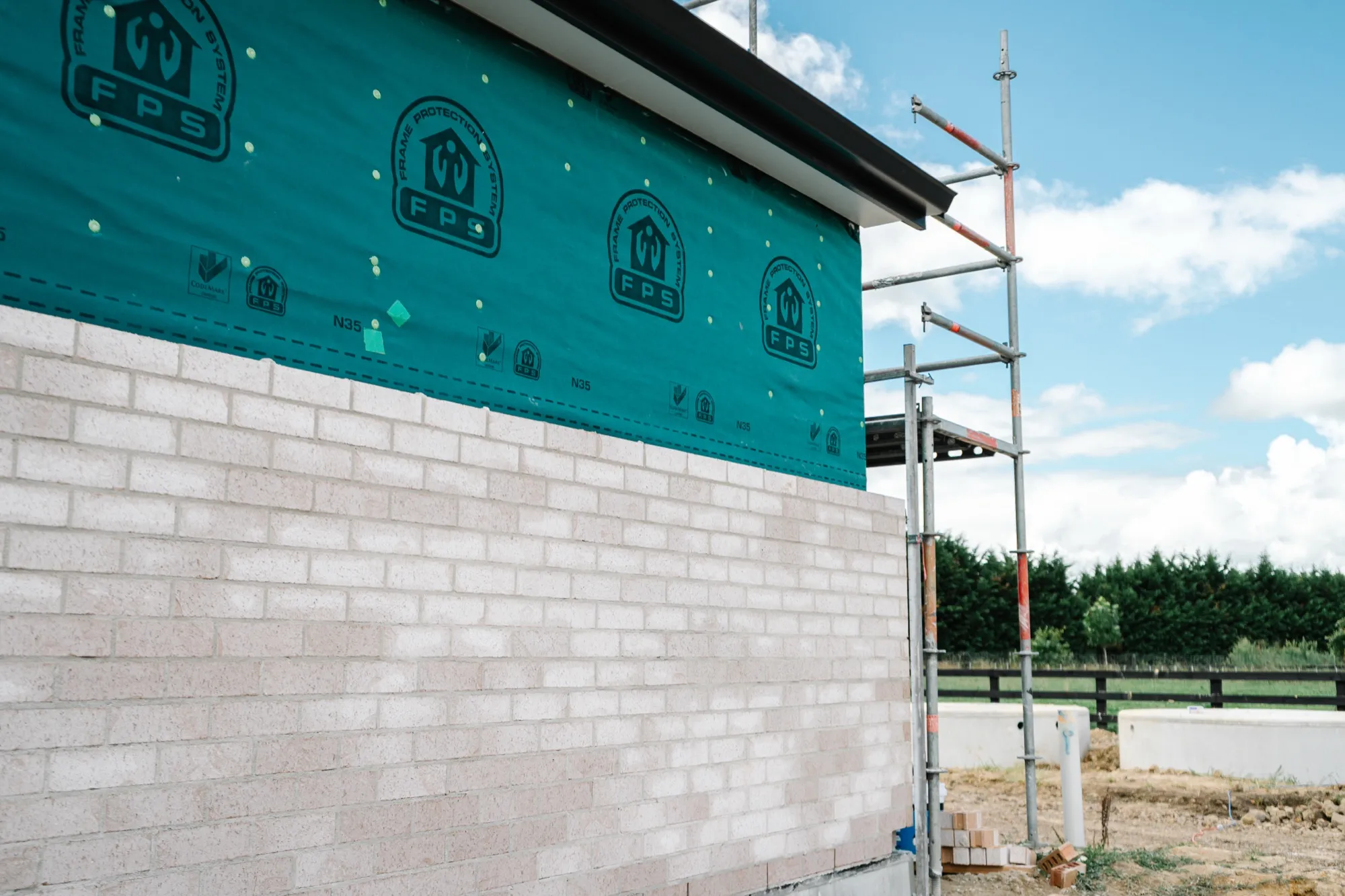 A finished run of brick cladding with blue sky beyond the scaffold