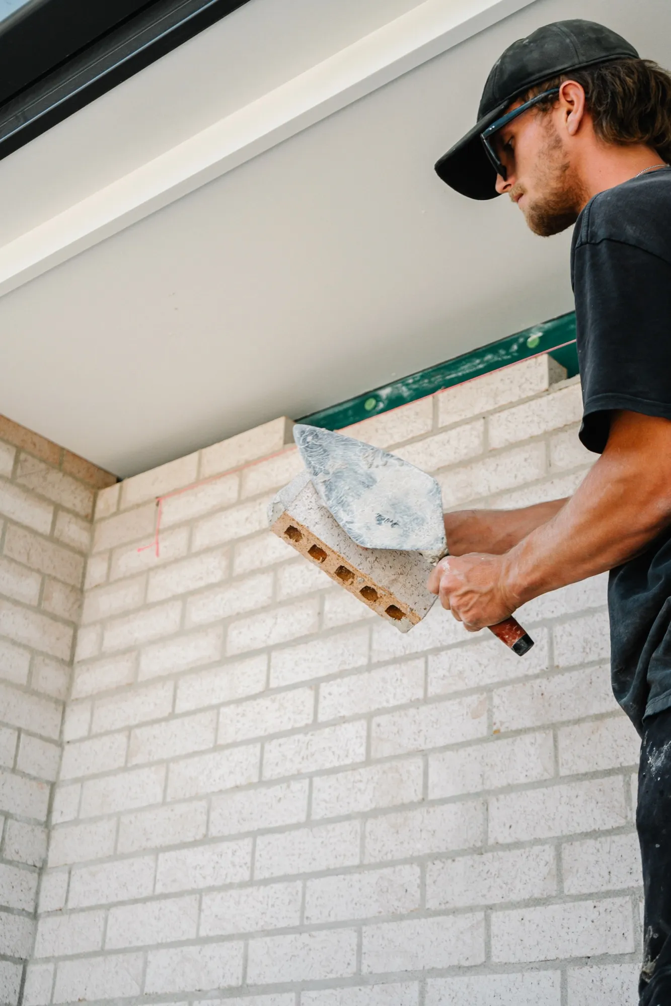 A bricklayer setting a brick in place under the soffit