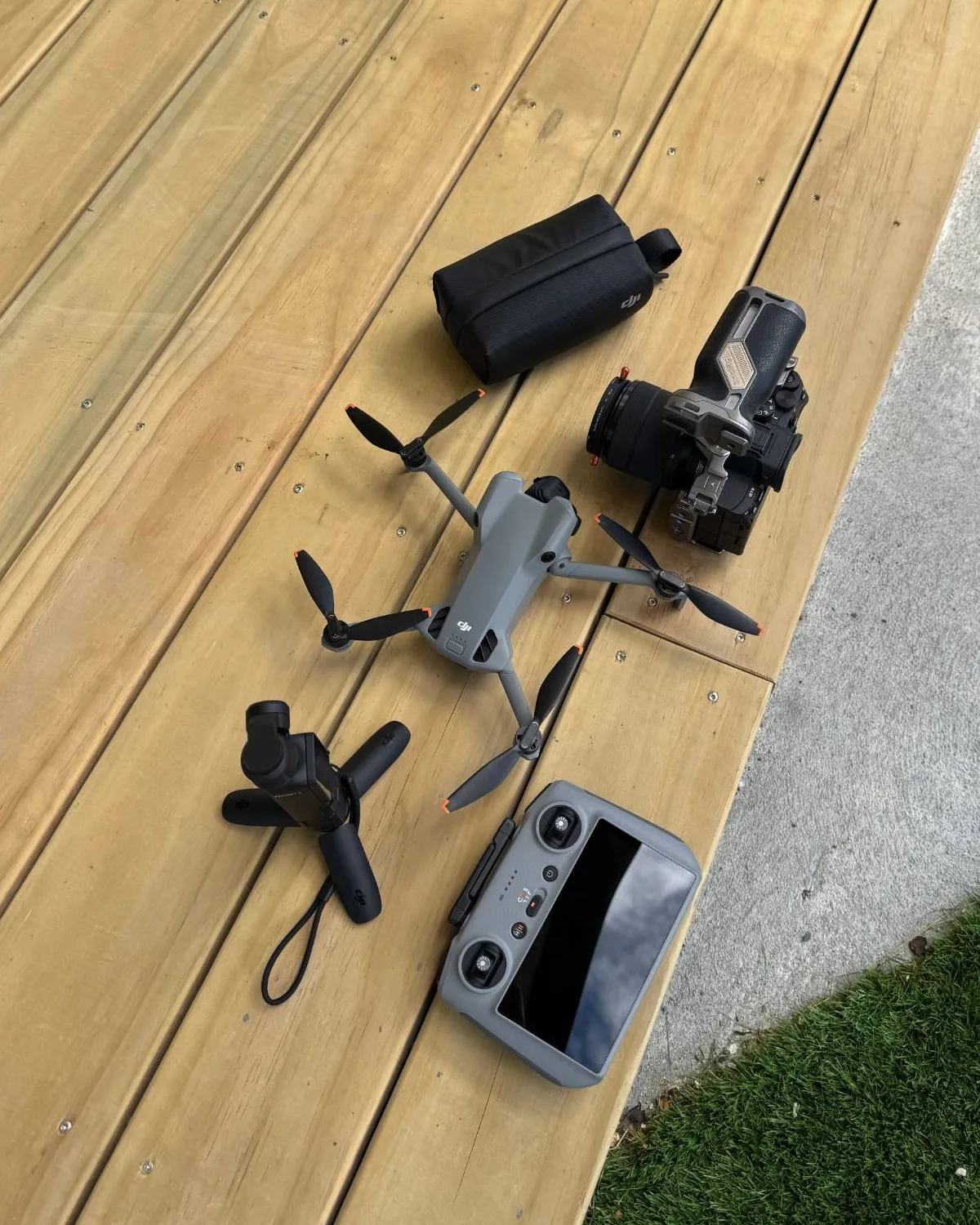 A drone, camera, gimbal and controller laid out on a deck before a shoot
