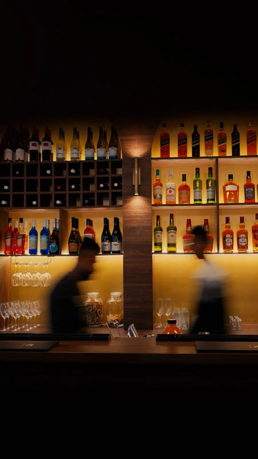 Staff moving past the lit back bar at Kolombo