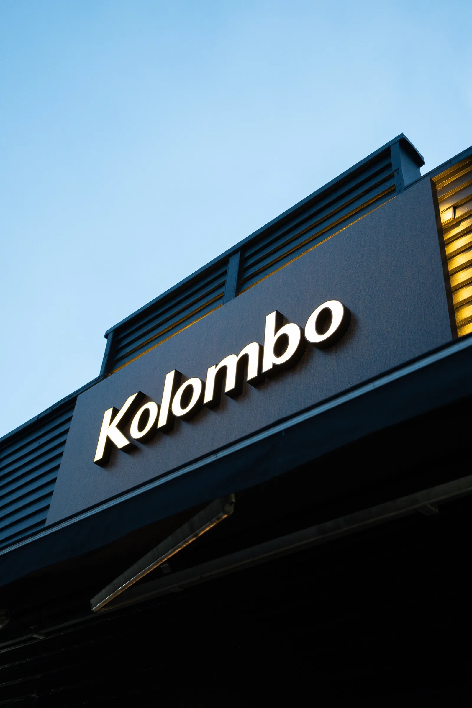 The Kolombo sign on the building against a blue sky