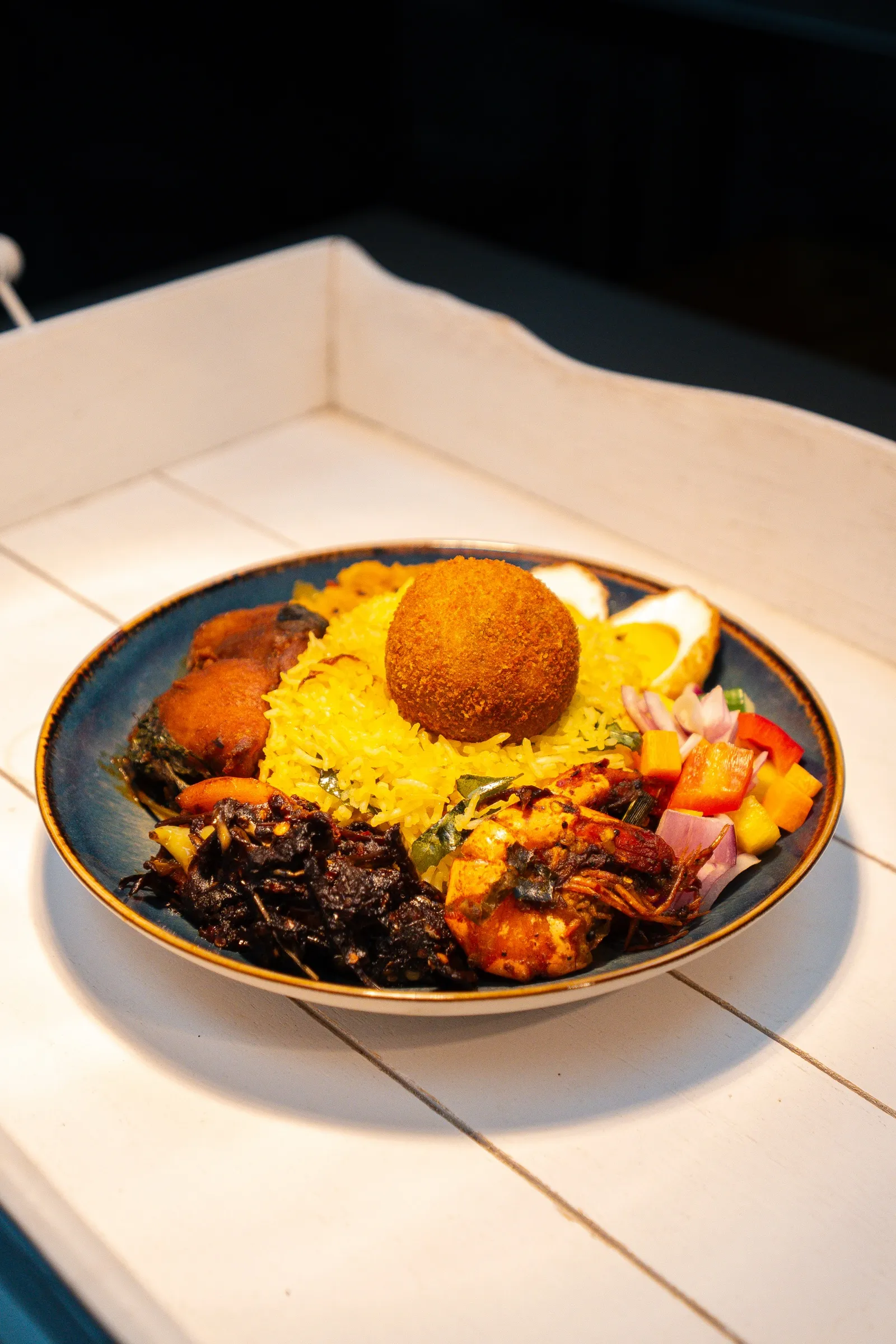 A plated rice dish with curries and sambols