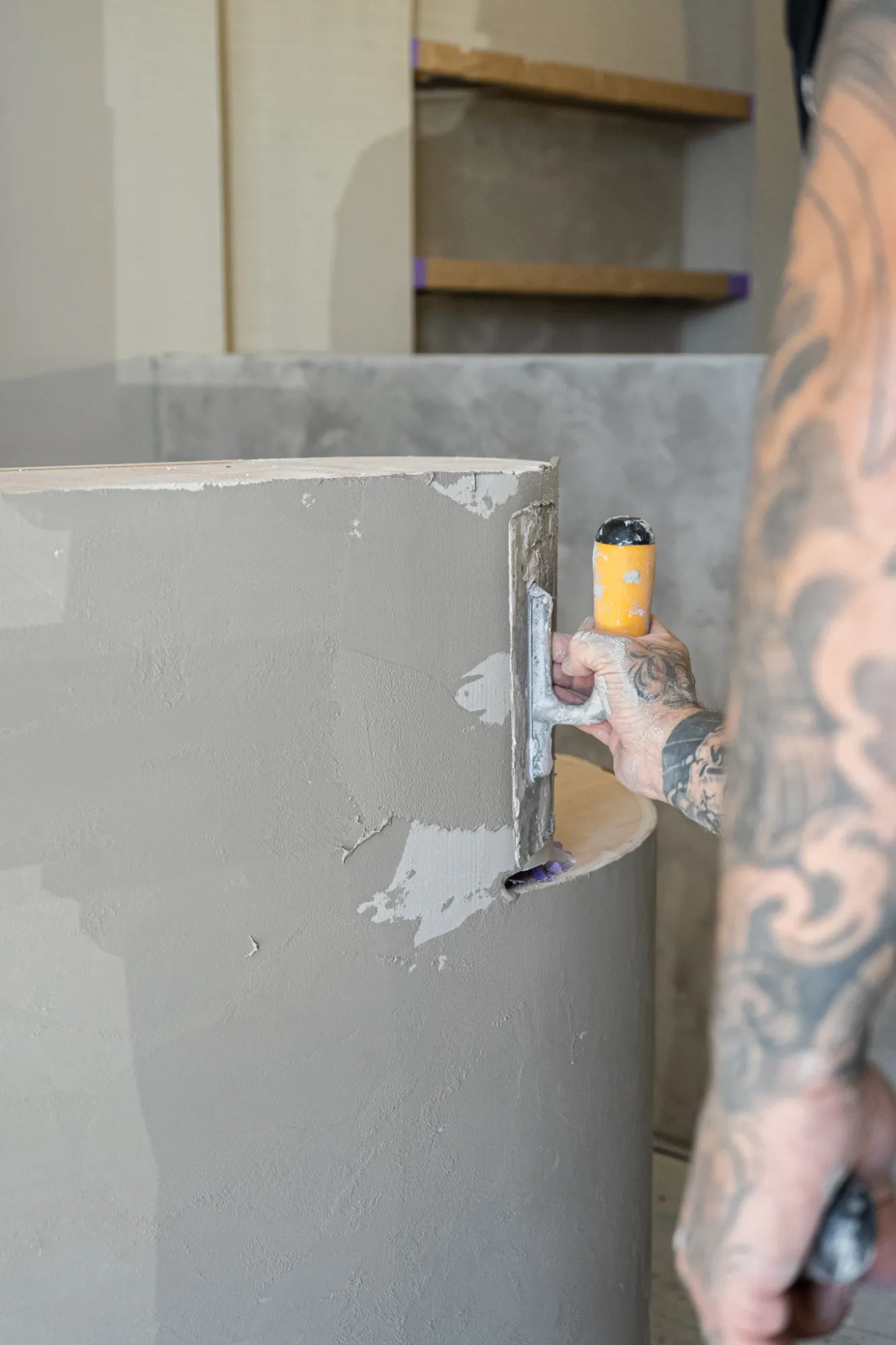 A trowel smoothing plaster around a curved reception desk