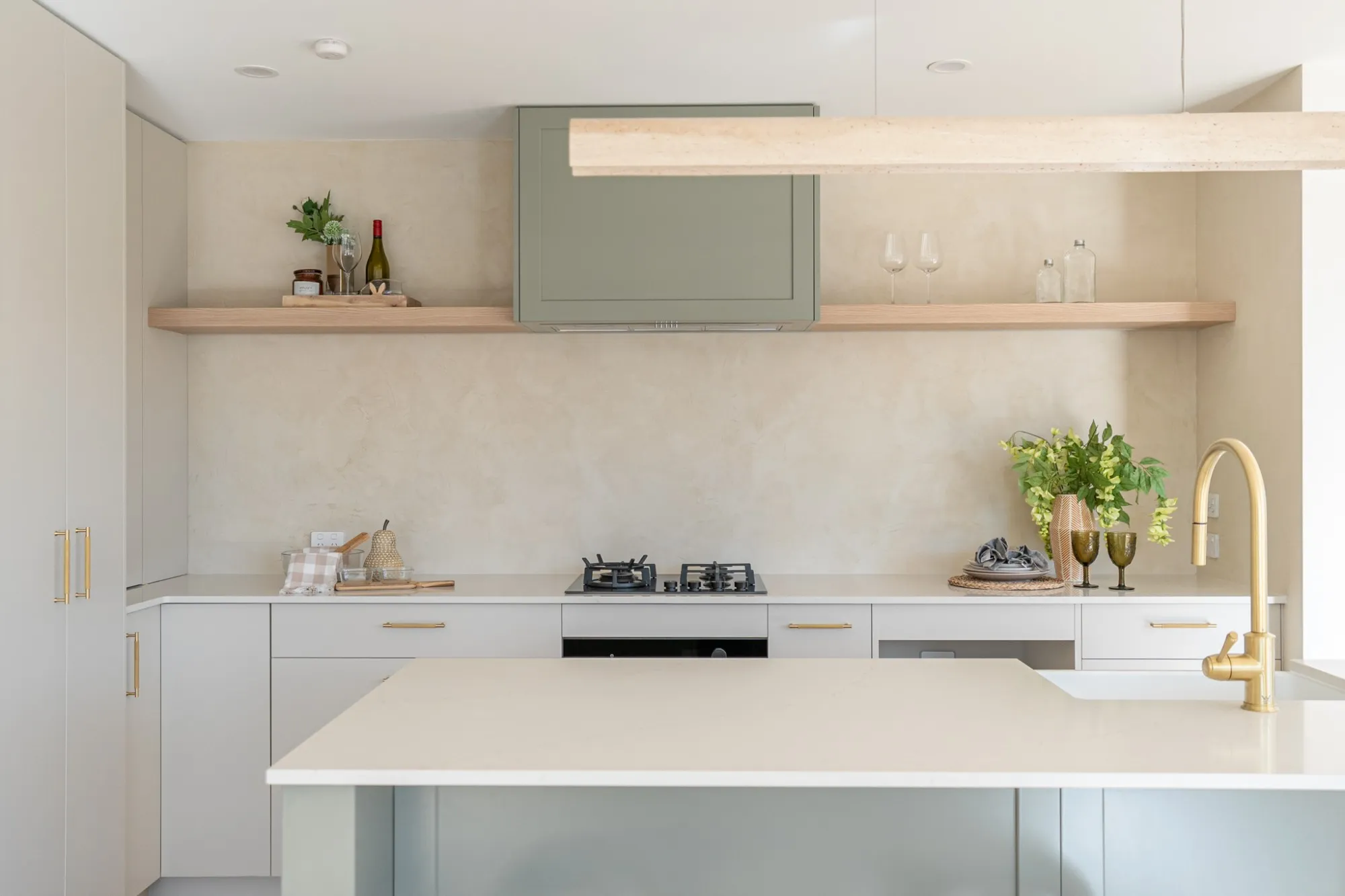 A kitchen with a Venetian plaster splashback and open timber shelf