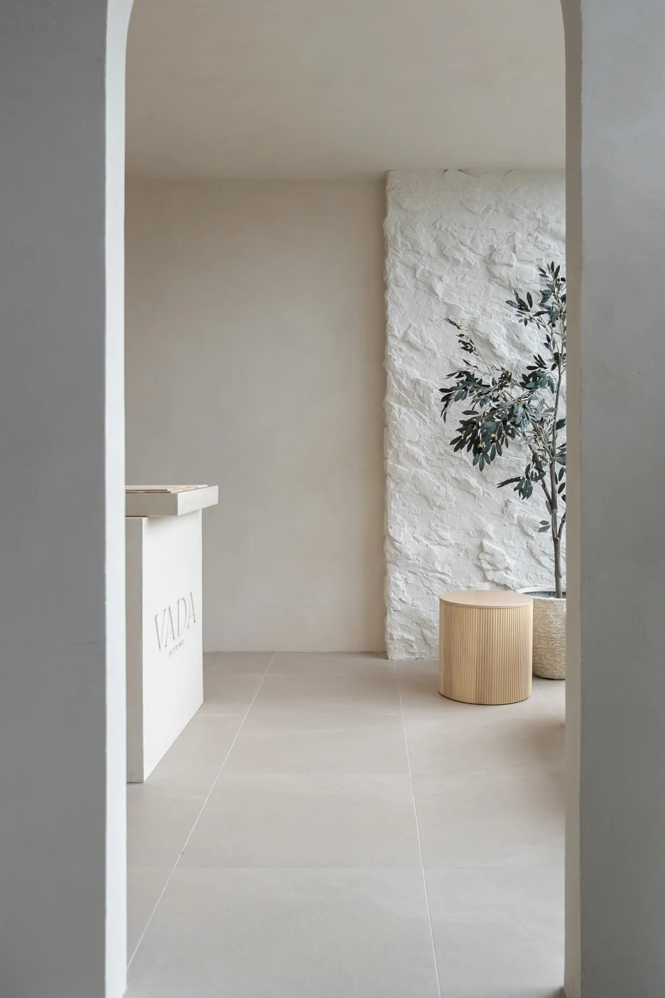 An arched doorway looking into the Vada Interiors showroom and its textured feature wall