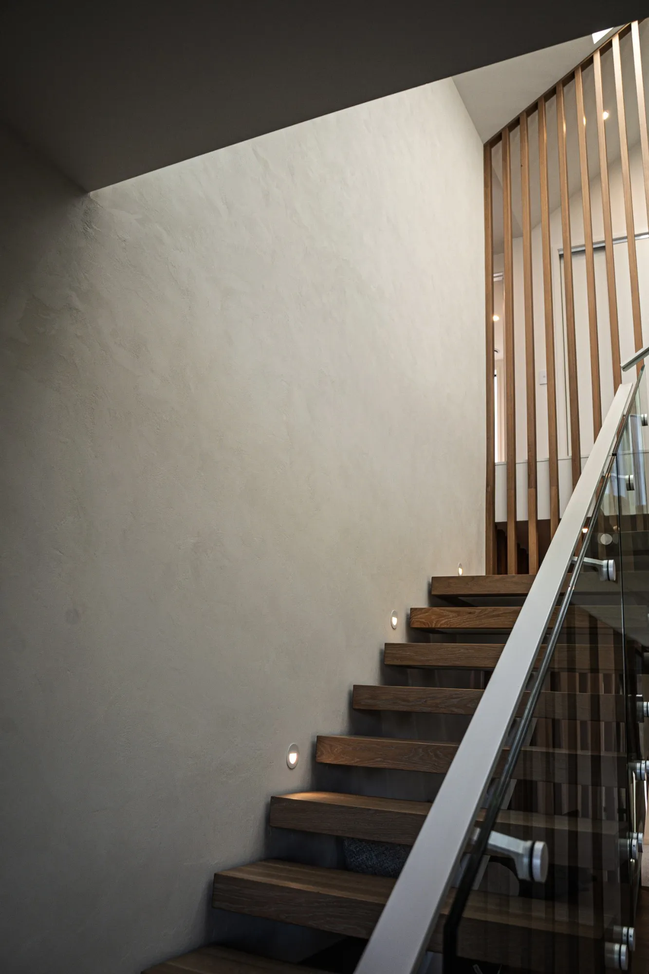 A stairwell finished in Venetian plaster beside timber stairs