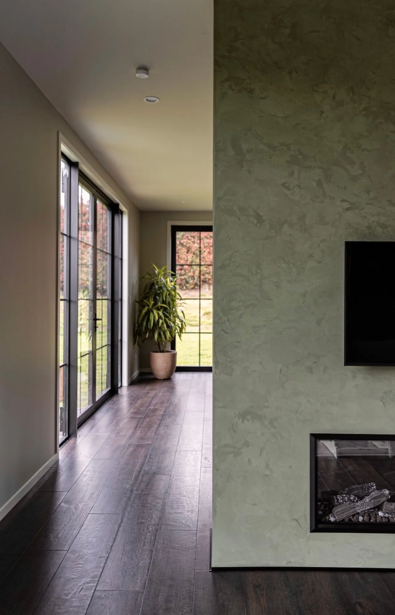 Green Venetian plaster feature wall with a built-in fireplace, finished by Vada Interiors