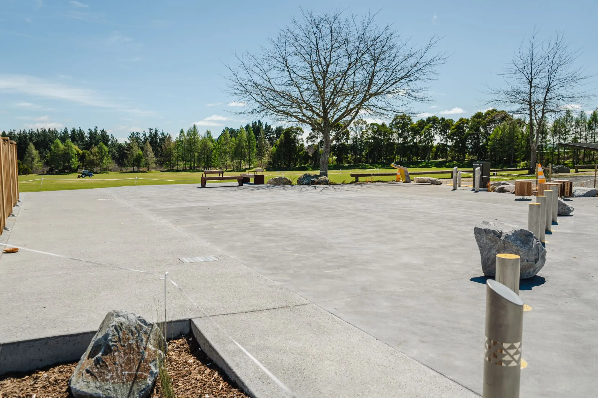 A finished concrete plaza beside a sports field