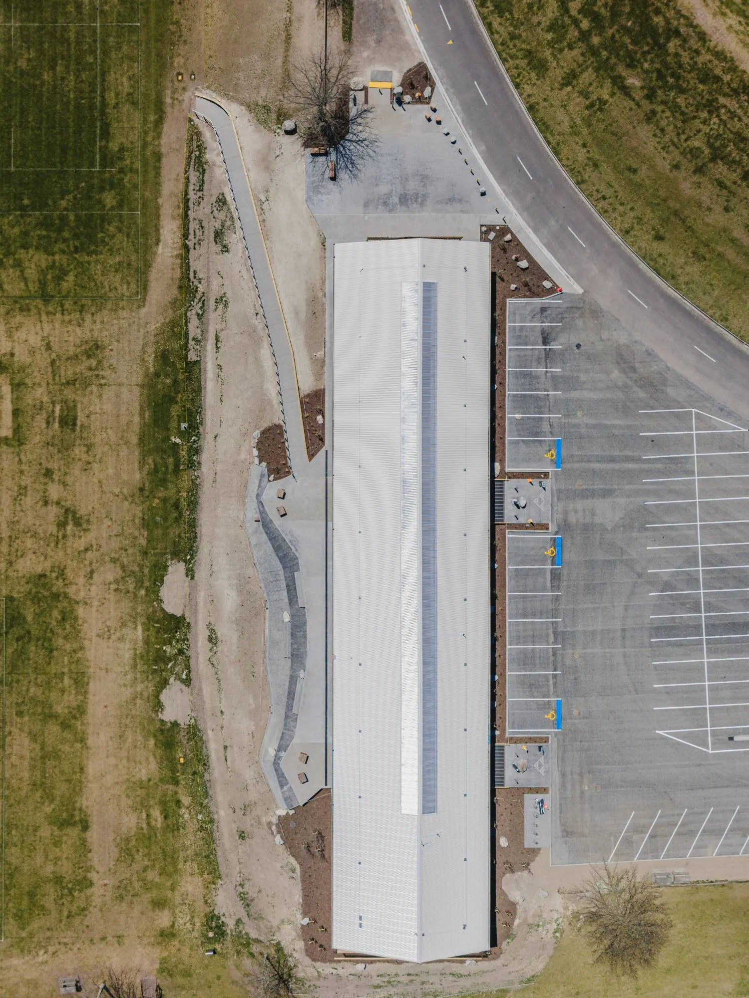 Aerial view of a long sports pavilion with new concrete paths
